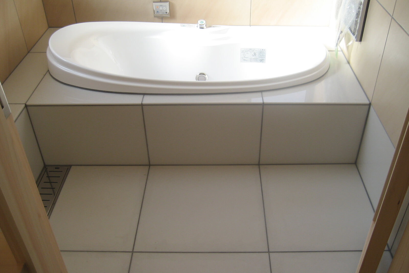 浴室床面と浴槽周りにハイブリッドストーン アベイラス アンプロップ ホワイト色が施工されている