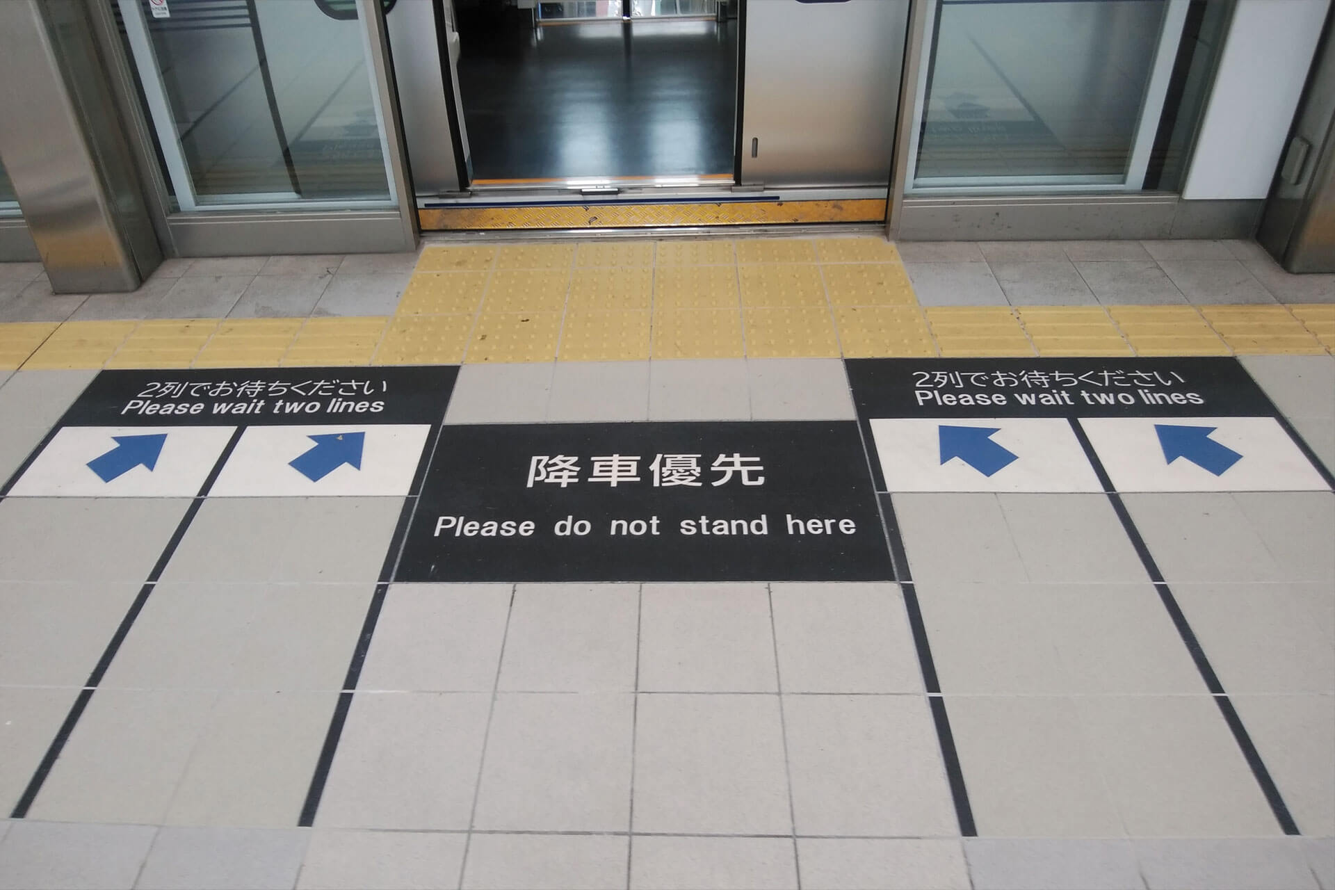 新橋駅のホームに施工された「2列でお待ちください」「降車専用」と表示されたハイブリッドストーン アベイラス アンプロップを正面から見た拡大図