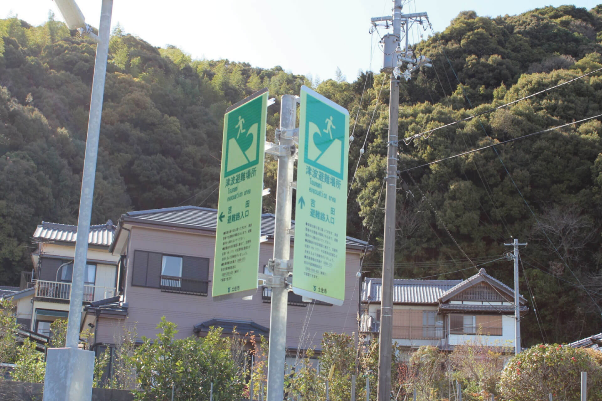 高知県土佐市の住宅地に設置されている吉田避難路入口と表記された2枚のアベイラス アルシオール サインプレート（高輝度蓄光式屋外用案内標示板）