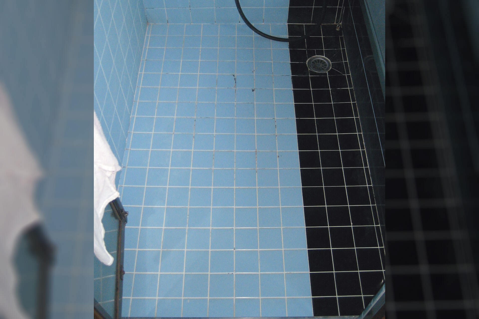 ハイブリッドストーン アベイラス スーパー浴室床材で改修する前の青と黒のタイル床
