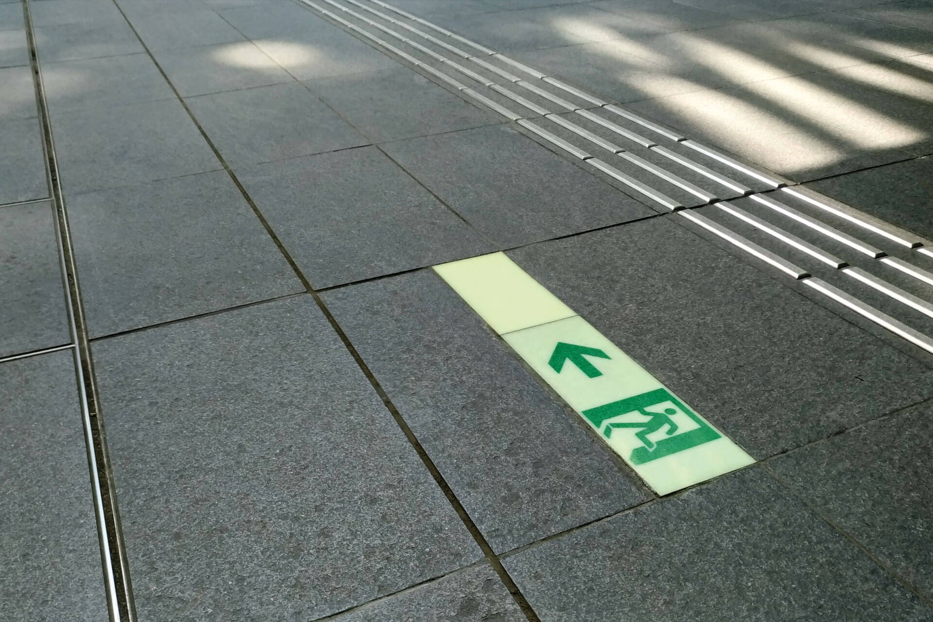 東京大学2号館の床に施工された点字ブロック横のハイブリッドストーン アベイラス アルシオール高輝度蓄光式誘導標識（消防避難設備認定品）